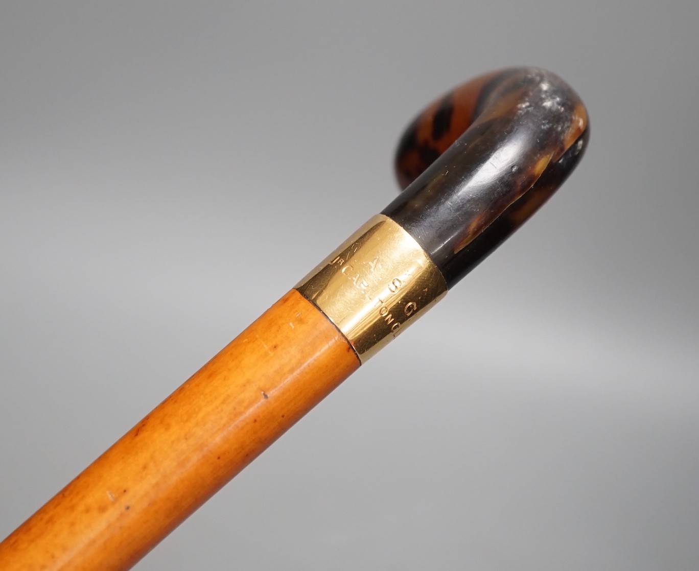 An 18ct gold collared malacca cane, with a horn handled handle, stained as tortoiseshell, 94 cms long
